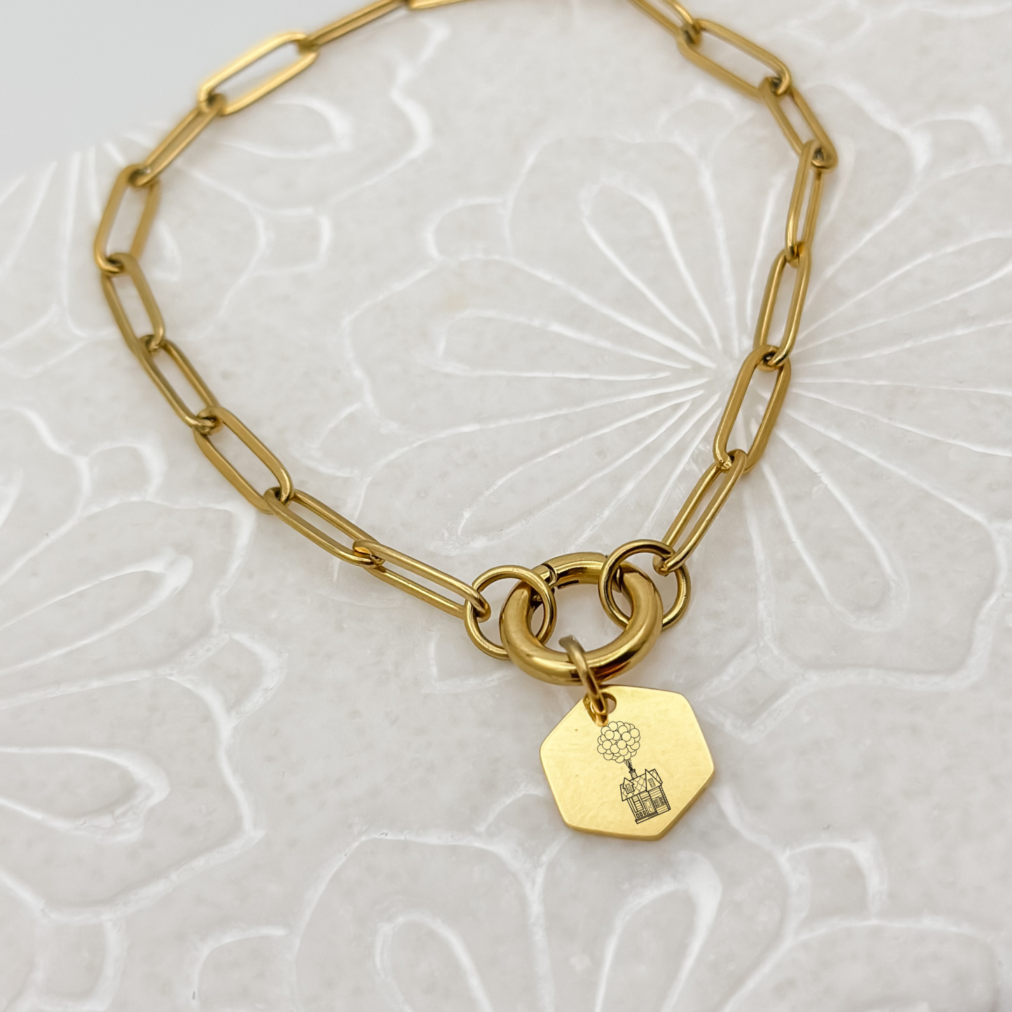 Floating House Charm Bracelet on a gold paperclip chain with a charm keeper. Hexagon Charm featuring an engraved House with Balloons helping it float UP in the air. Hypoallergenic, waterproof, stainless steel jewelry.