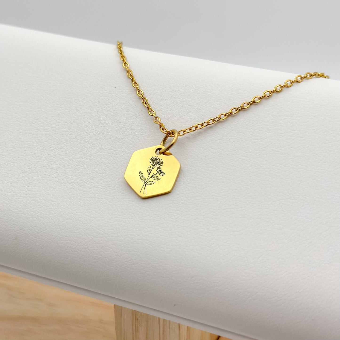 18K PVD Gold hexagon charm necklace featuring a hand-drawn daisy engraving, the birth flower for April. Hypoallergenic, waterproof, and tarnish-resistant.