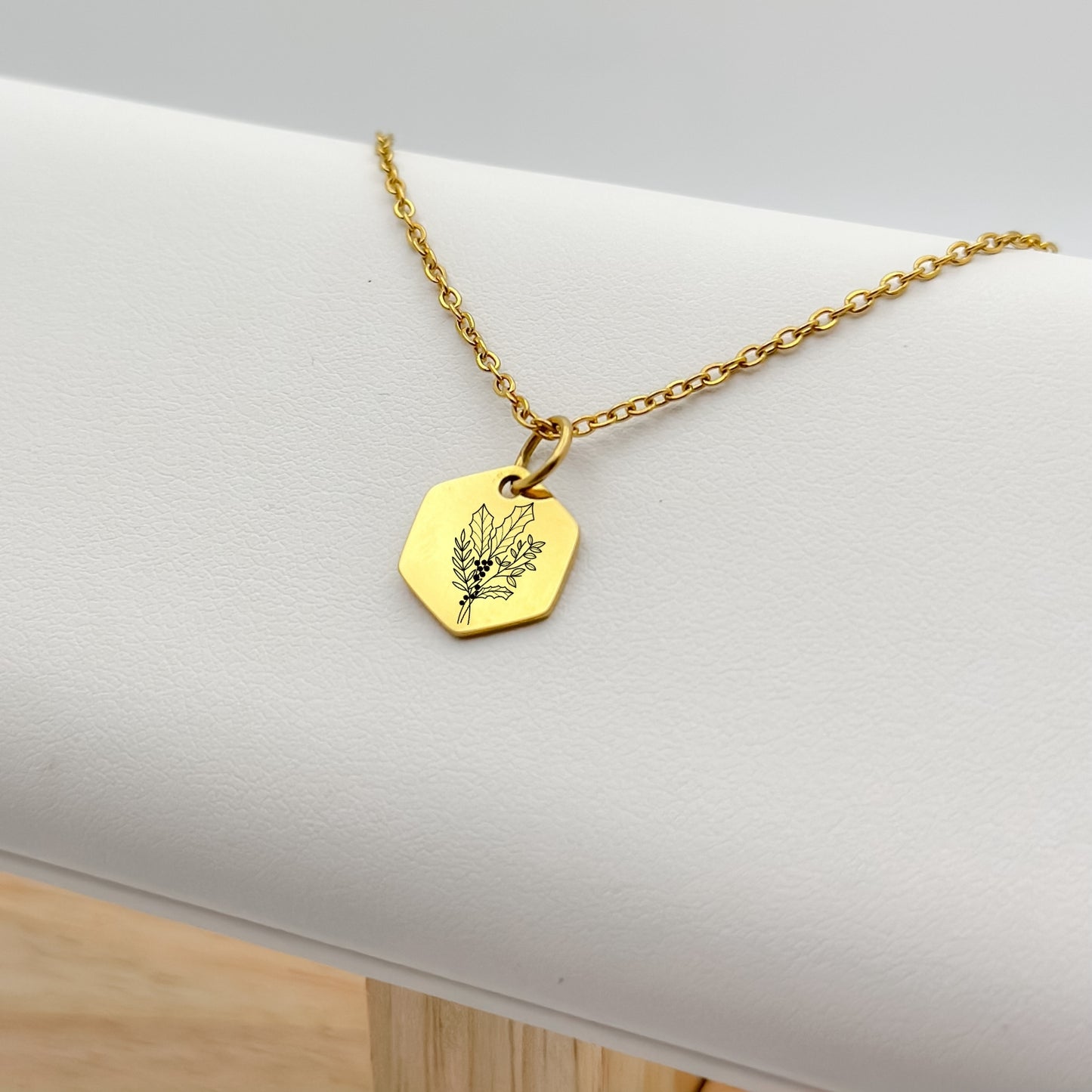18K PVD Gold hexagon charm necklace featuring a hand-drawn holly branch engraving, the birth flower for December. Hypoallergenic, waterproof, and tarnish-resistant.