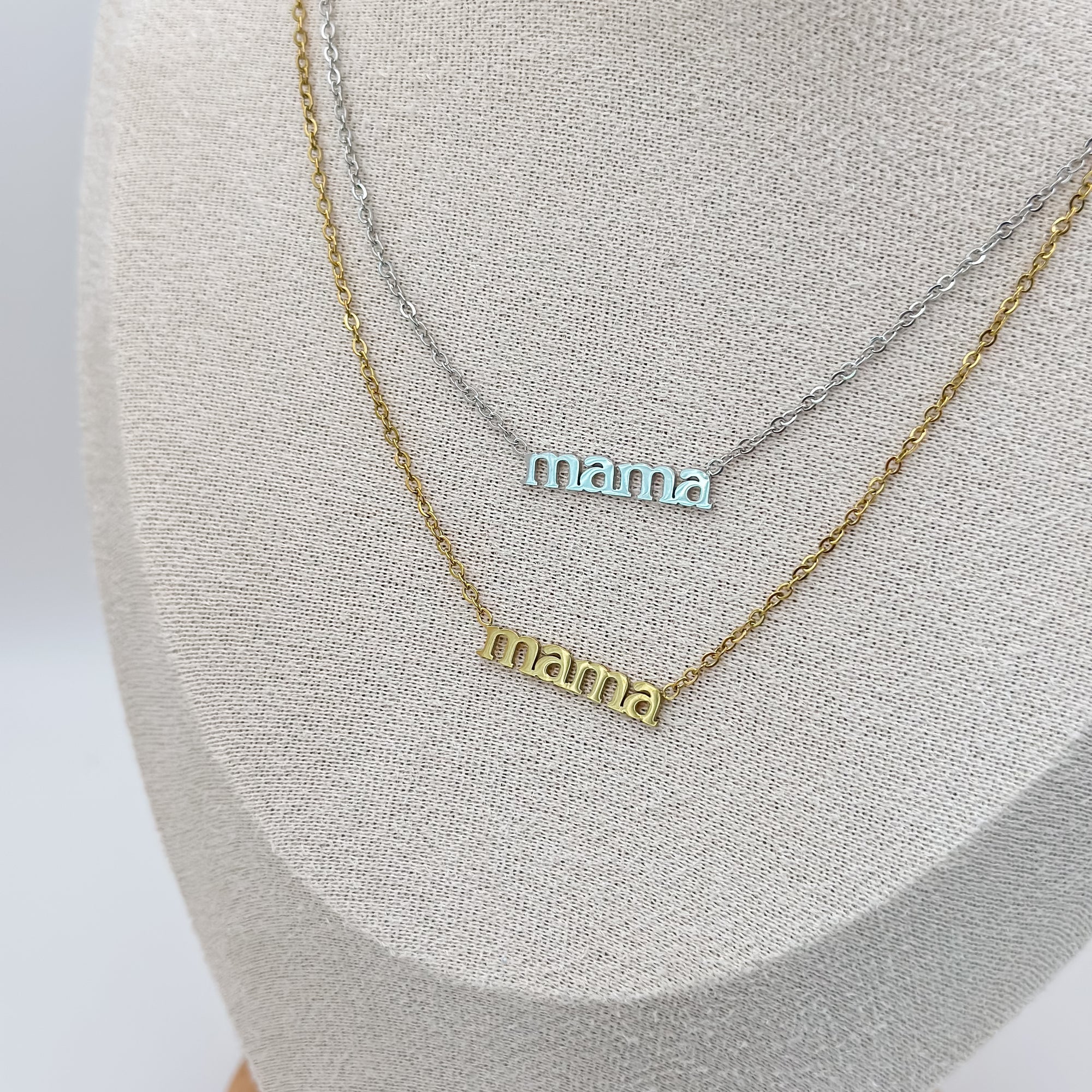 Two 'mama' necklaces on a gray surface