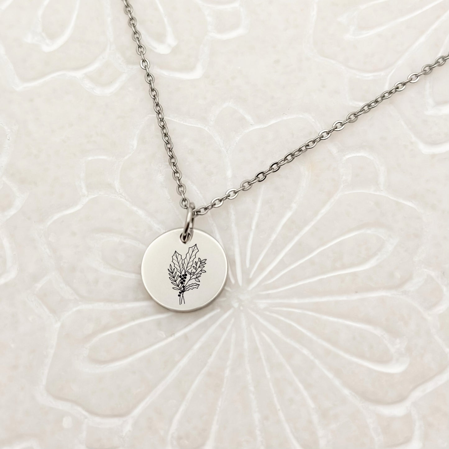 Minimalist silver circle charm necklace with a beautifully engraved holly branch, the December birth flower. Hypoallergenic, waterproof, and tarnish-resistant.