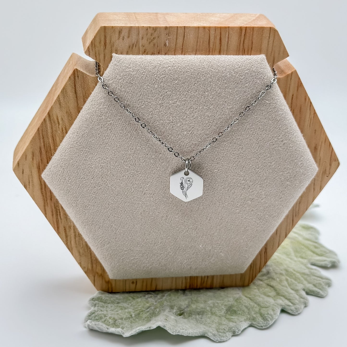 Silver hexagon charm necklace engraved with a poppy, the August birth flower. Hypoallergenic, waterproof, and tarnish-resistant.