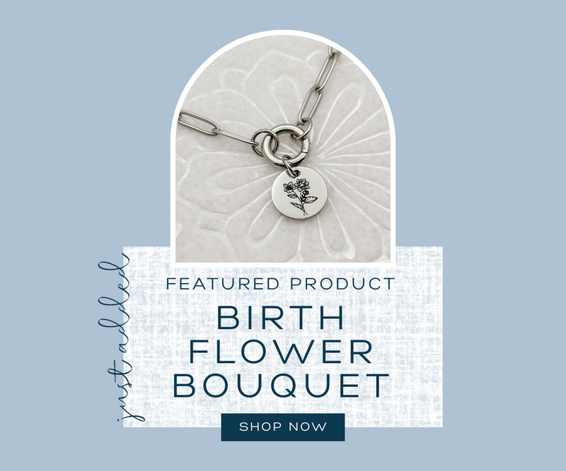 Silver necklace with a circular pendant featuring a birth flower design on a light blue background.