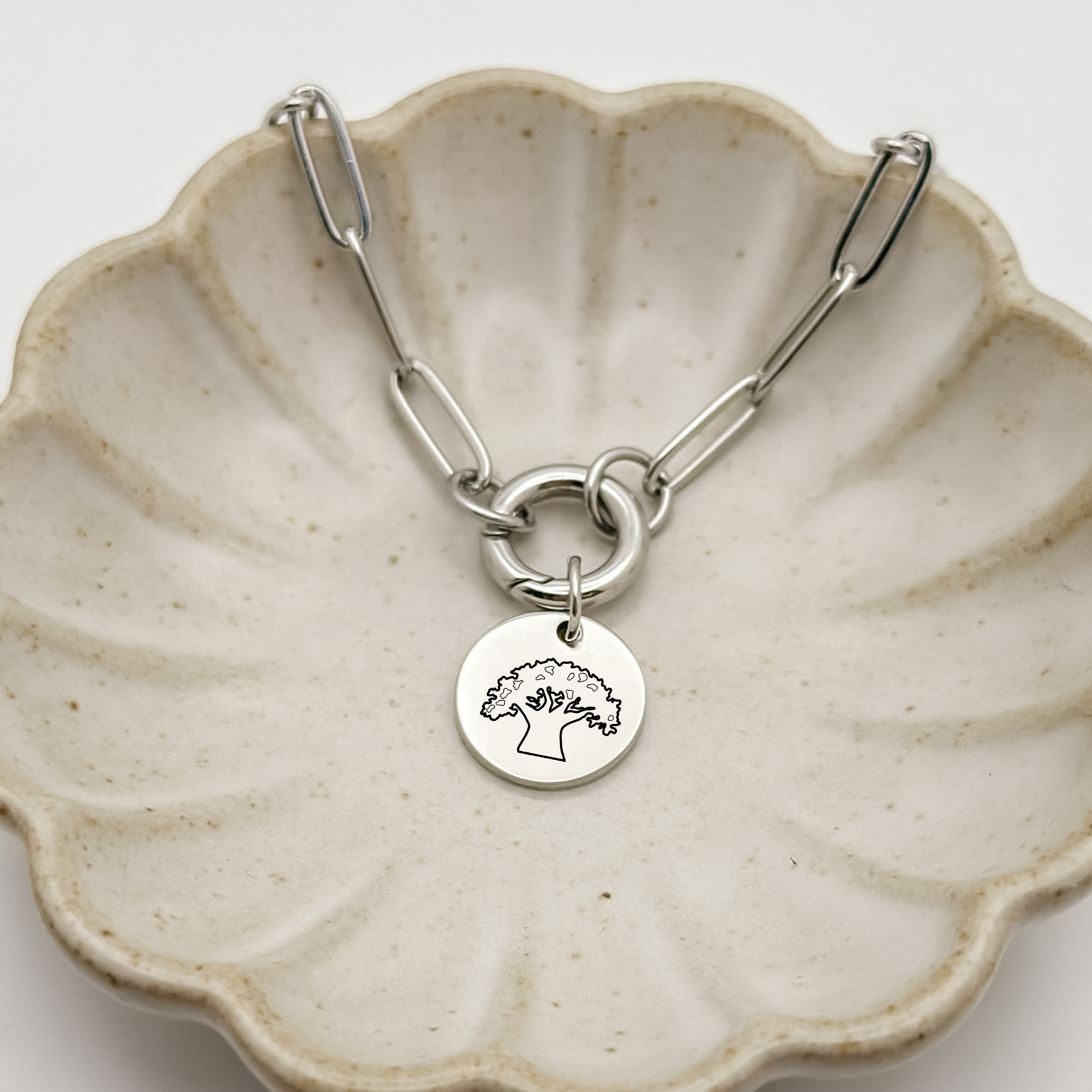 Animal K Charm Bracelet on a paperclip chain with charm keeper. Silver Circle Charm featuring an engraved Tree of Life. Hypoallergenic, waterproof, stainless steel jewelry. 