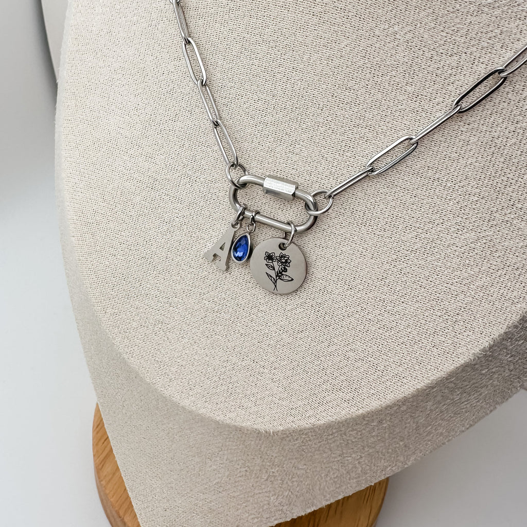 Silver necklace with charms on a wooden stand