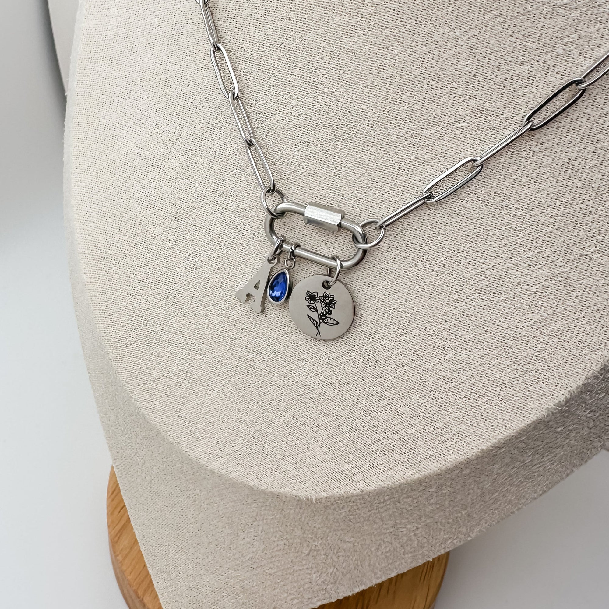 Silver necklace with charms on a wooden stand