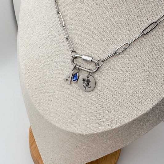Silver necklace with charms on a wooden stand