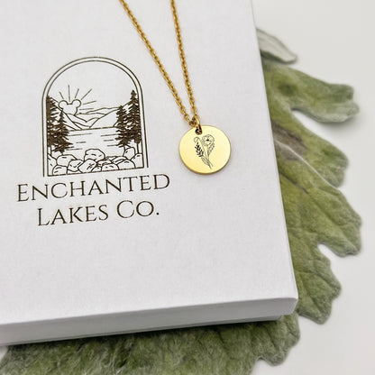 Elegant 18K PVD Gold circle charm necklace featuring a detailed poppy engraving, symbolizing August birthdays. Hypoallergenic, waterproof, and tarnish-resistant.