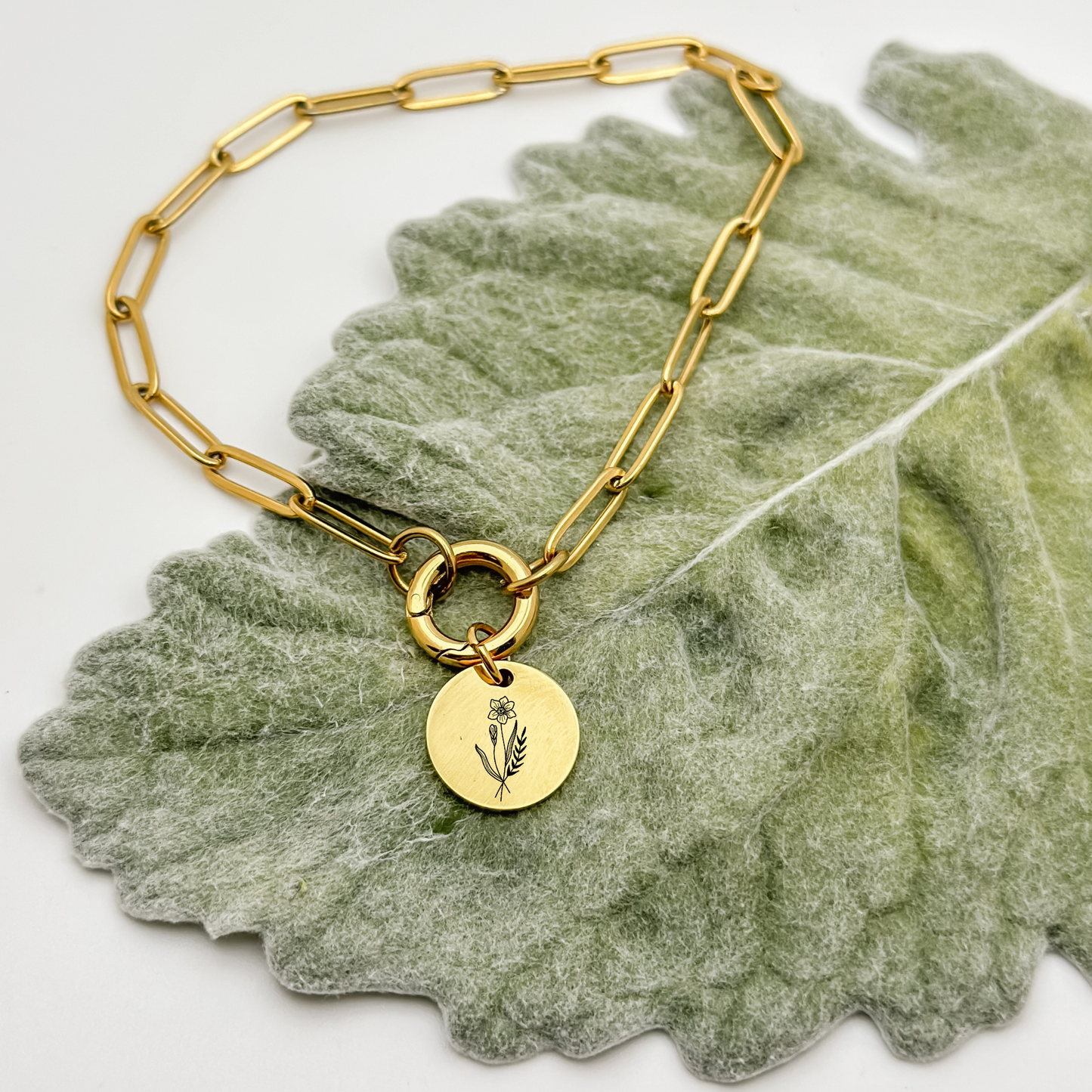 Personalized 18K PVD Gold circle charm with an engraved daffodil, representing March birthdays, on a charm keeper necklace. Hypoallergenic, waterproof, and tarnish-resistant.