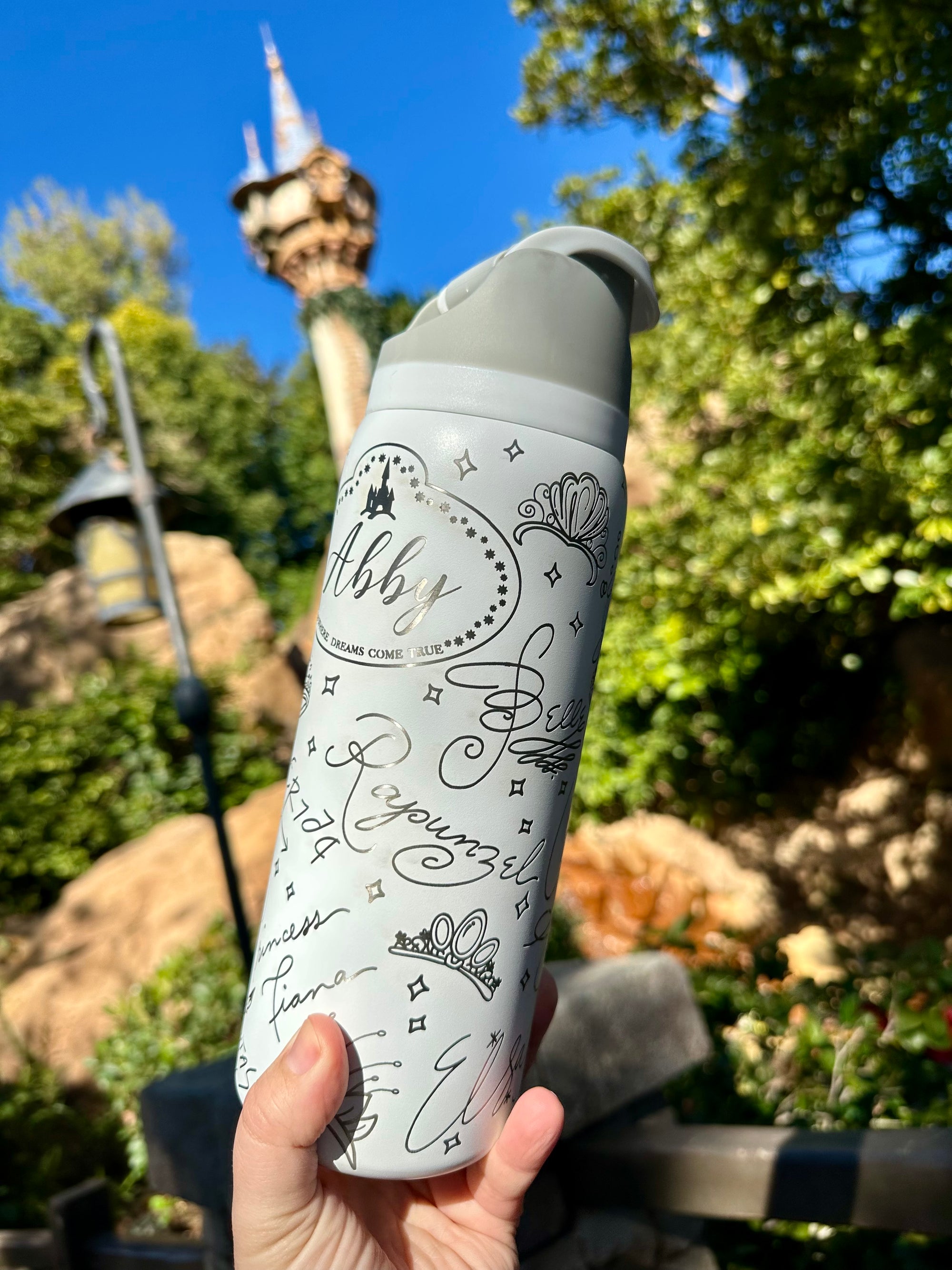 White water bottle with decorative text held in front of a scenic background