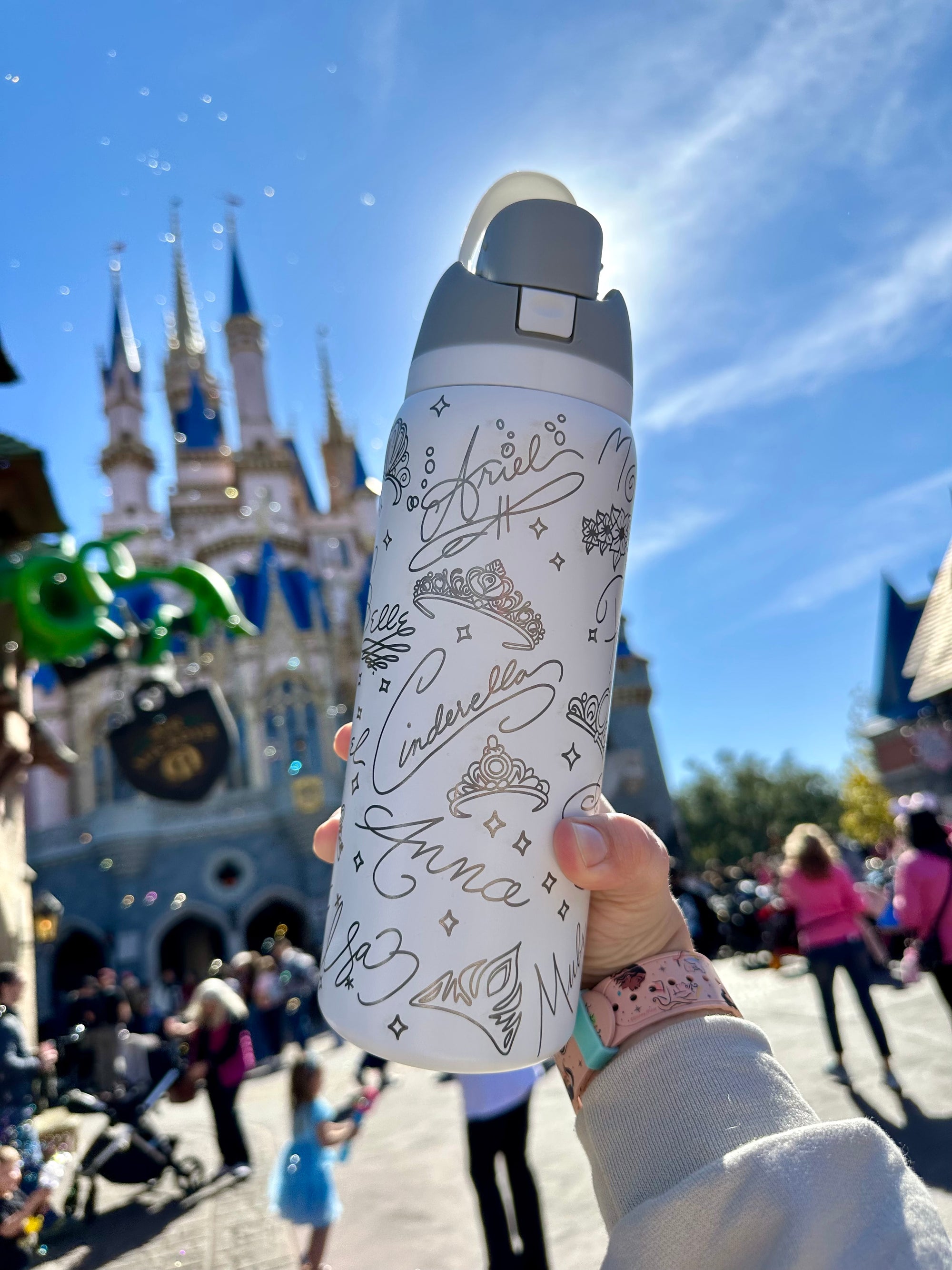 White water bottle with black designs held in front of a castle.