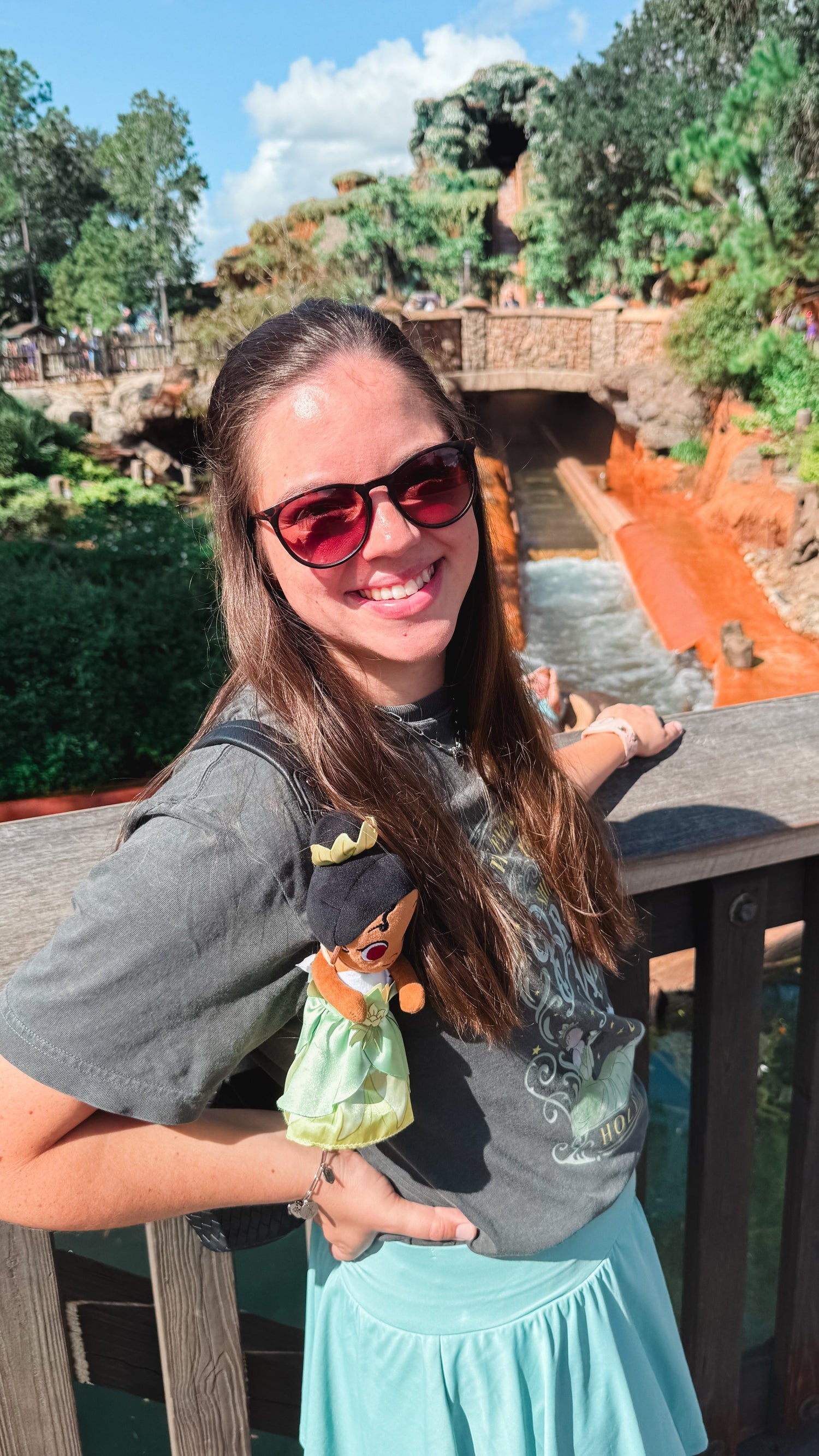 Photo of Abby, owner and designer of Enchanted Lakes Co., standing in front of a magical ride at Disney World, radiating joy and creativity.