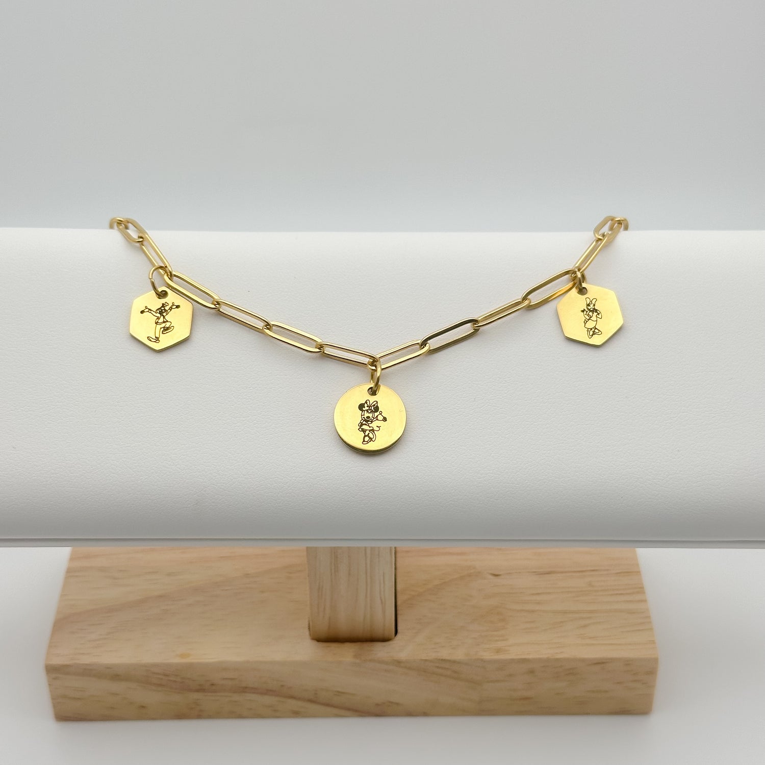 gold minimalist charm bracelet on a paperchip chain. containing three charms, miss mouse, silly dog and miss duck