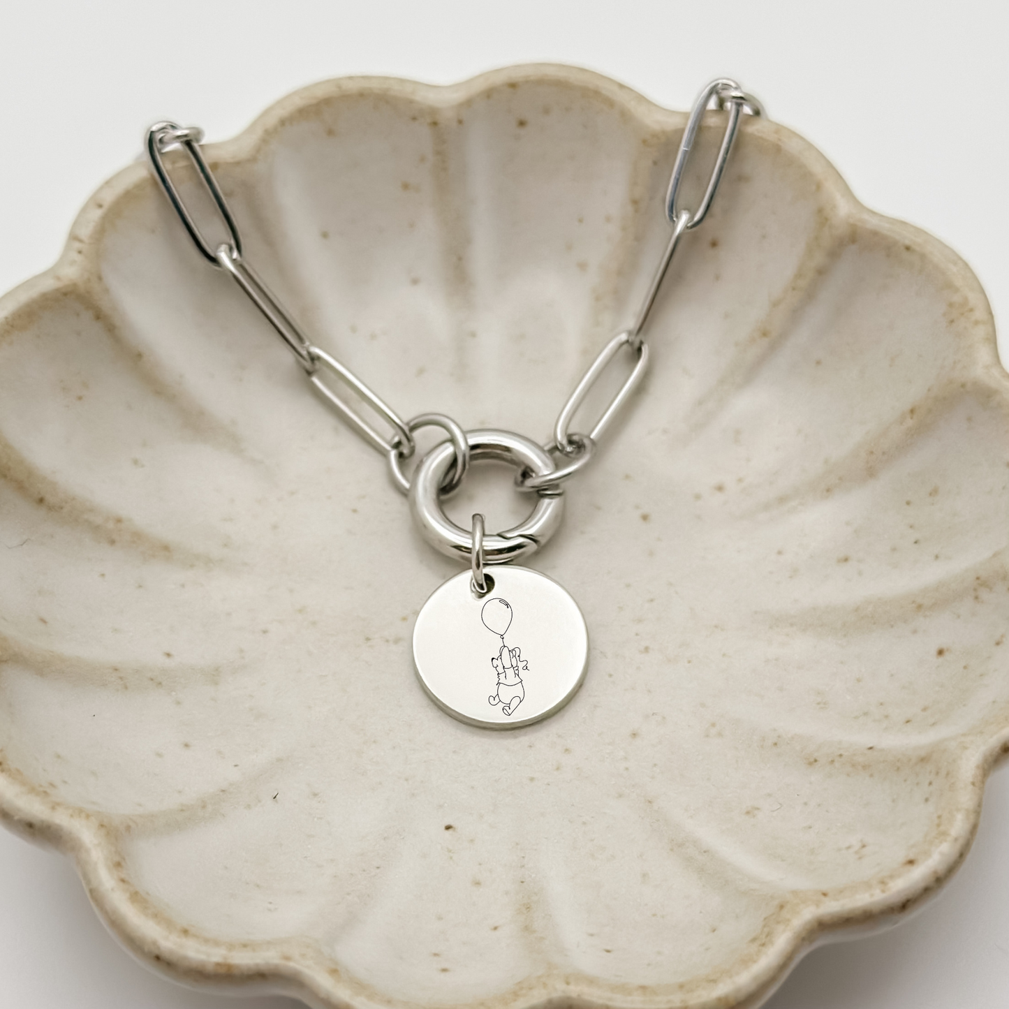 Silver Honey Bear Charm Bracelet on a paperclip chain with a charm keeper. Silver Circle Charm featuring an engraved Honey Bear holding on to a balloon. Hypoallergenic, waterproof, stainless steel jewelry. 