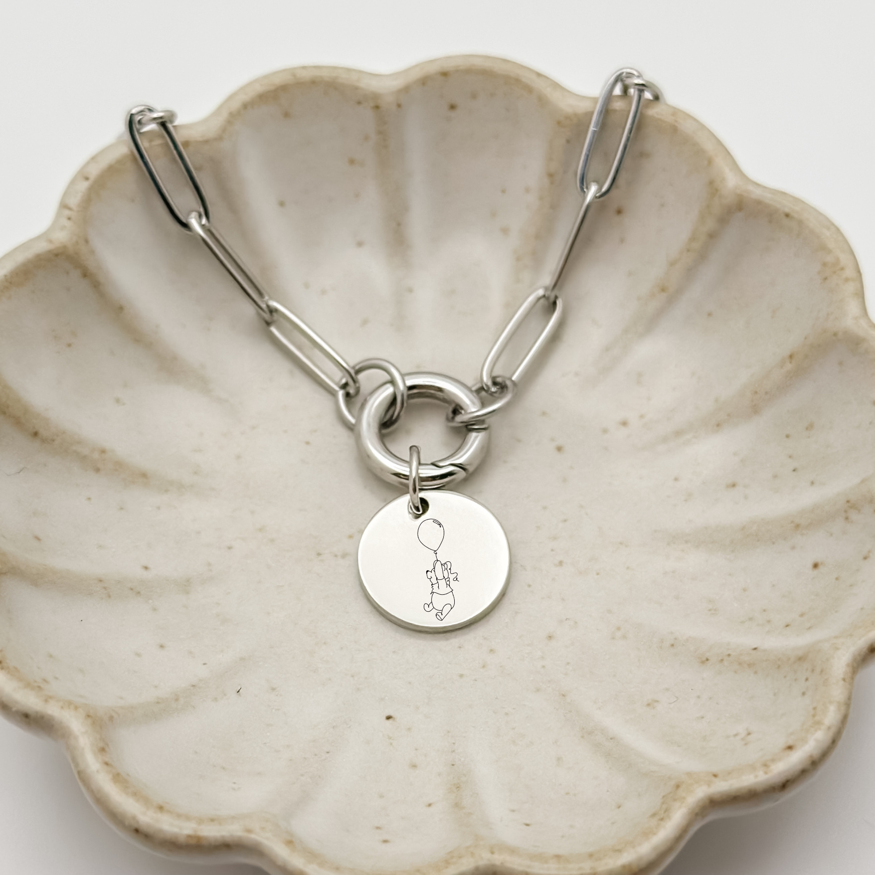 Silver Honey Bear Charm Bracelet on a paperclip chain with a charm keeper. Silver Circle Charm featuring an engraved Honey Bear holding on to a balloon. Hypoallergenic, waterproof, stainless steel jewelry. 