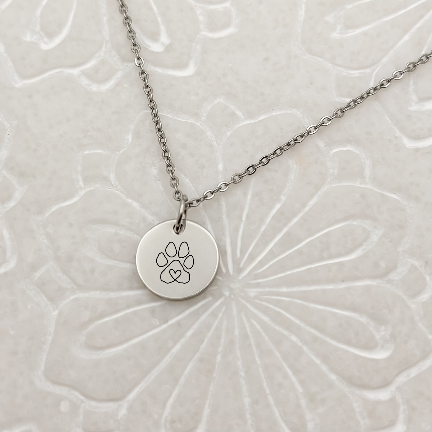 Elegant silver circle charm with a minimalist paw print on a classic loop chain necklace. Hypoallergenic, waterproof, and tarnish-resistant—perfect for pet lovers.