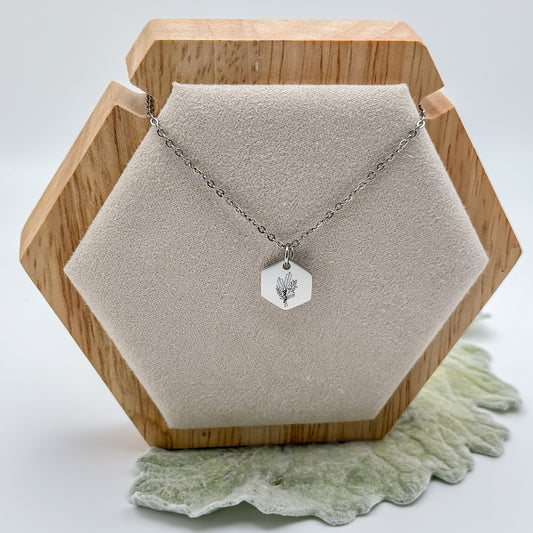 Silver hexagon charm necklace engraved with a holly branch, the December birth flower. Hypoallergenic, waterproof, and tarnish-resistant.