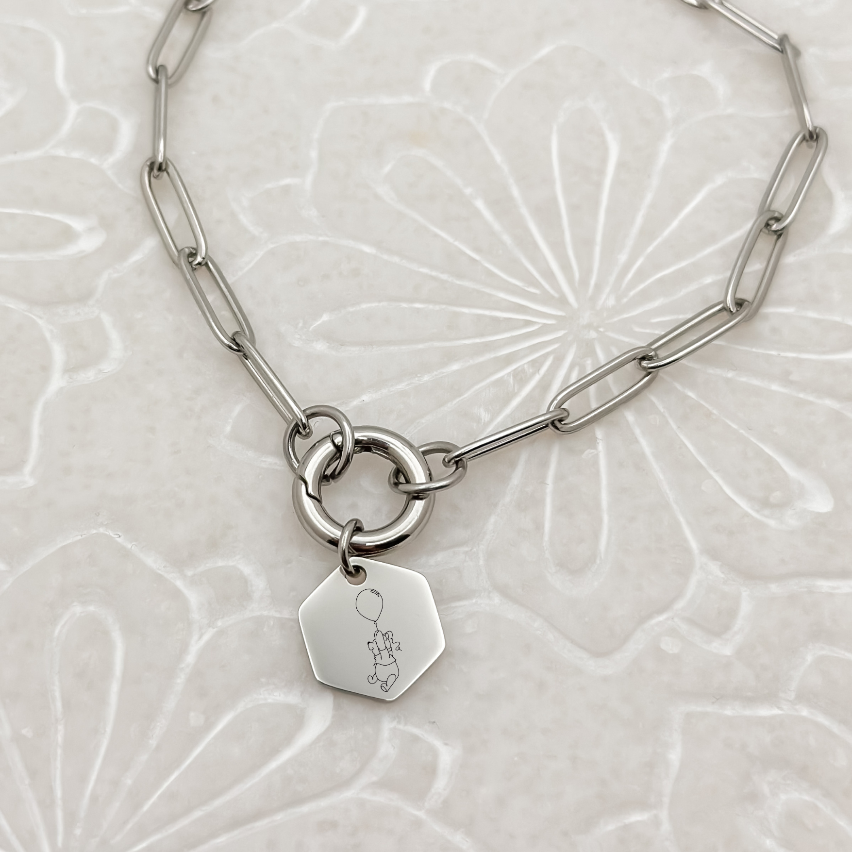 Silver Honey Bear Charm Bracelet on a paperclip chain on a charm keeper. Silver Hexagon Charm featuring an engraved Honey Bear holding on to a balloon. Hypoallergenic, waterproof, stainless steel jewelry. 