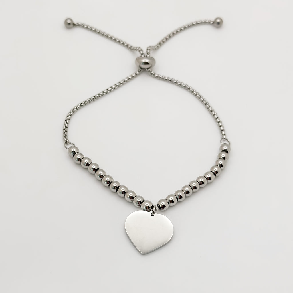 Silver beaded bracelet with a heart-shaped pendant on a light gray background