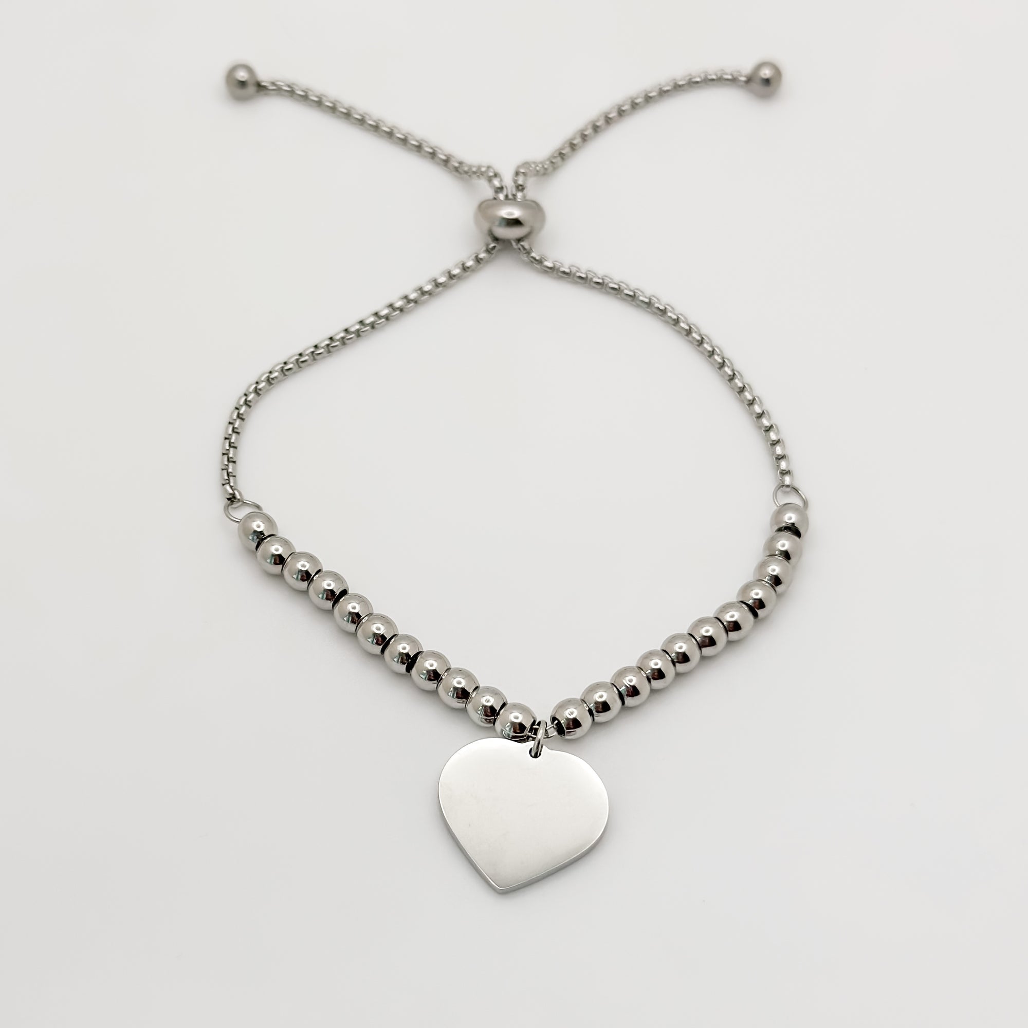 Silver beaded bracelet with a heart-shaped pendant on a light gray background